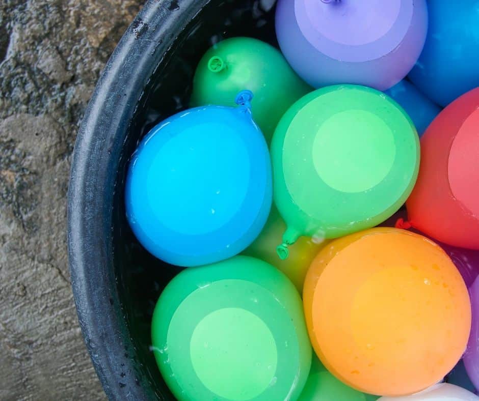 Colorful water balloons in a bucket of water.